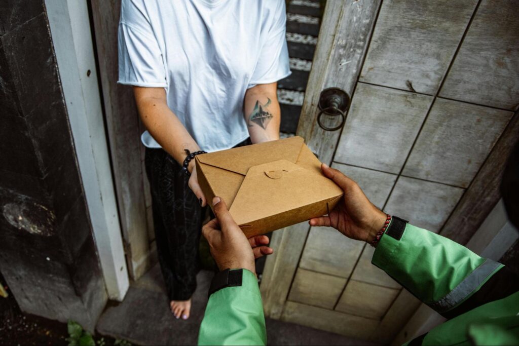 A delivery person handing a package to a person. Source - Pexels